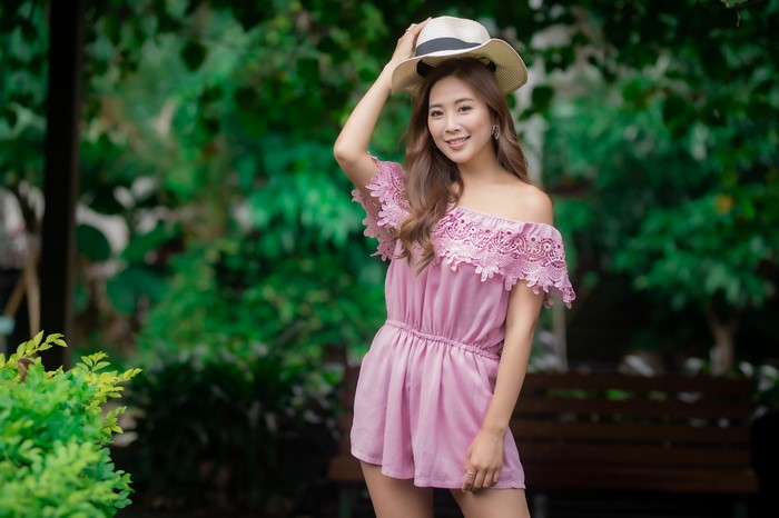 Asian woman in pink romper wearing a hat
