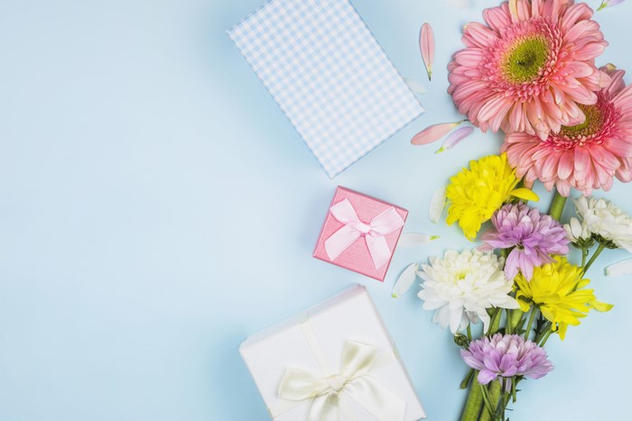 Gerberas and Chrysanthemums with Gifts on Blue Background