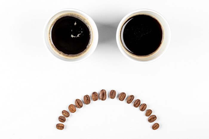 Two cups of coffee and coffee beans forming a sad face