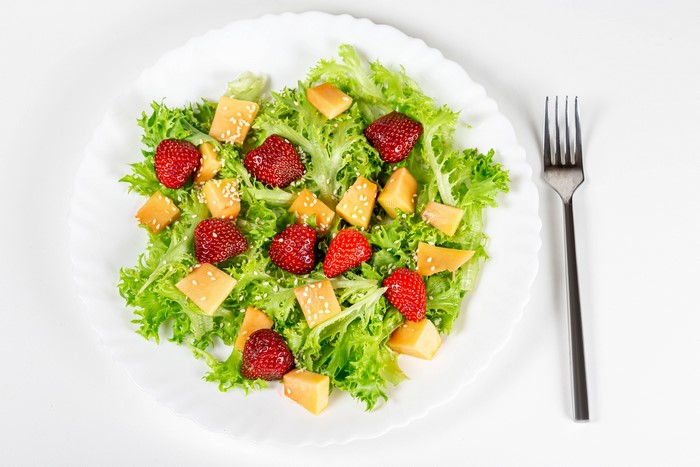 Salad with strawberries and cheese on a plate with a fork