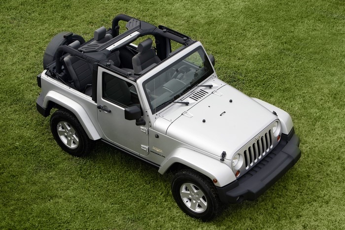 Silver Jeep Wrangler convertible on grass