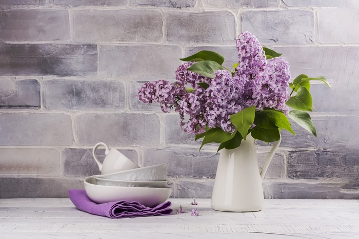 Lilac bouquet in a vase with cups and saucers