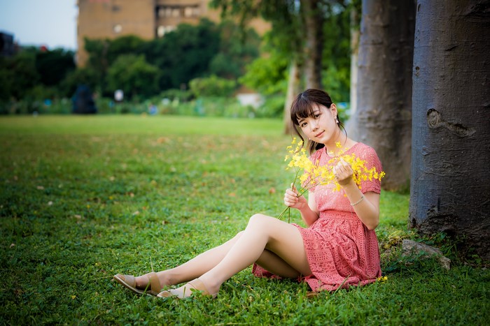 Asian woman sitting on grass with yellow flowers