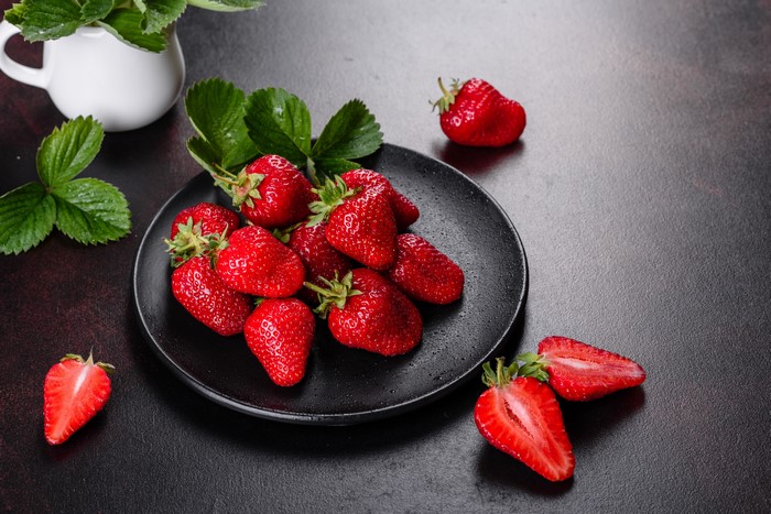 Strawberries on a black plate with foliage