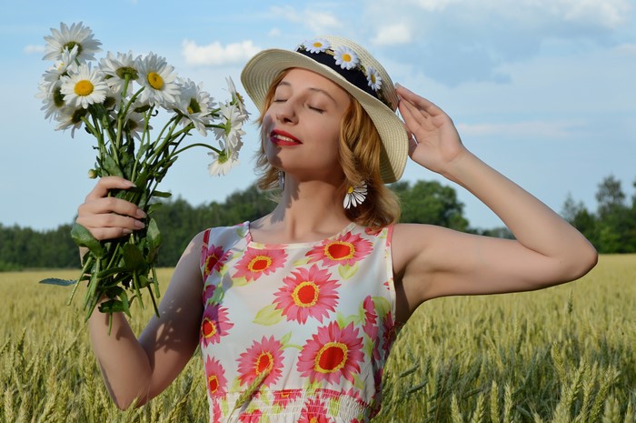 Girl with bouquet of camomiles in a field
