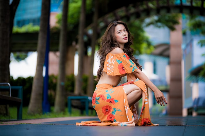 Asian woman with brown hair in orange floral dress