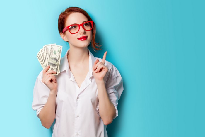 Redhead woman in glasses holding money