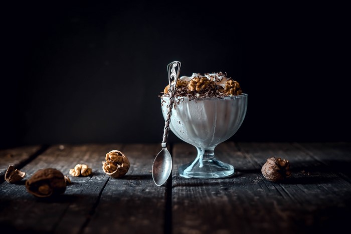 Ice cream with walnuts and chocolate shavings in a bowl with a spoon
