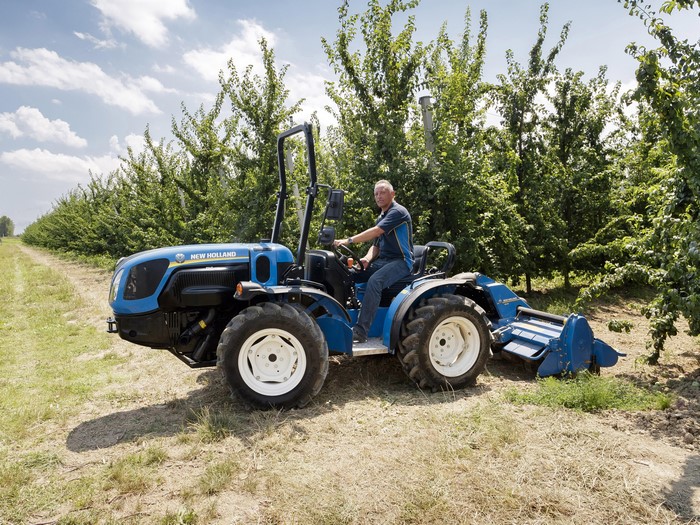 Man driving a New Holland tractor in an orchard