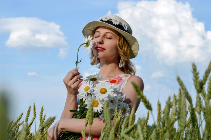Woman in Hat with Camomiles in Wheat Field