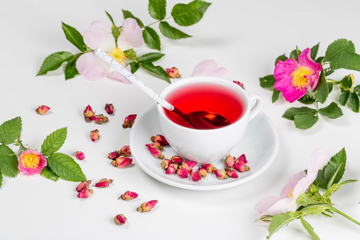 Cup of rose tea with dried roses and flowers