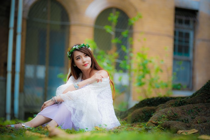 Asian woman with flower wreath sitting in grass