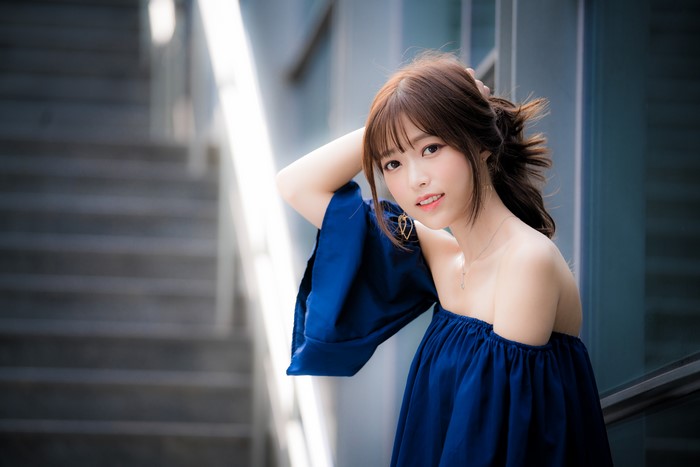 Asian woman with brown hair in blue off-the-shoulder top