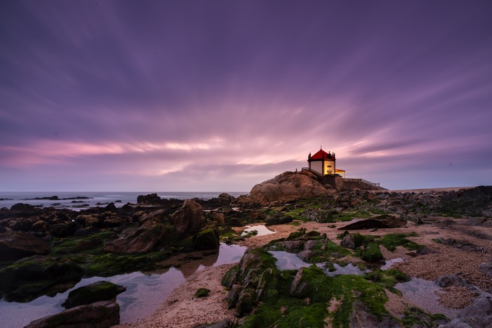 Capela do Senhor da Pedra church on rocky coast at sunset