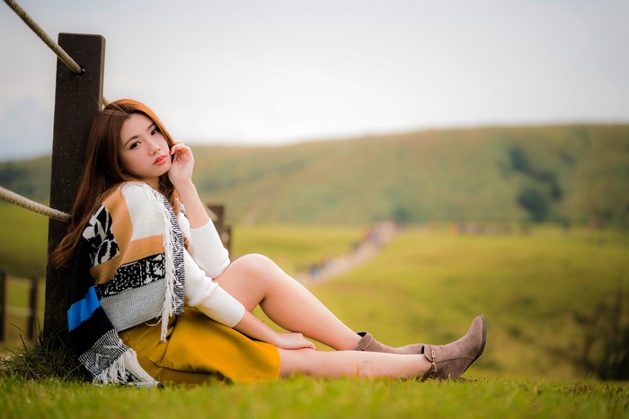 Asian woman with brown hair sitting on grass