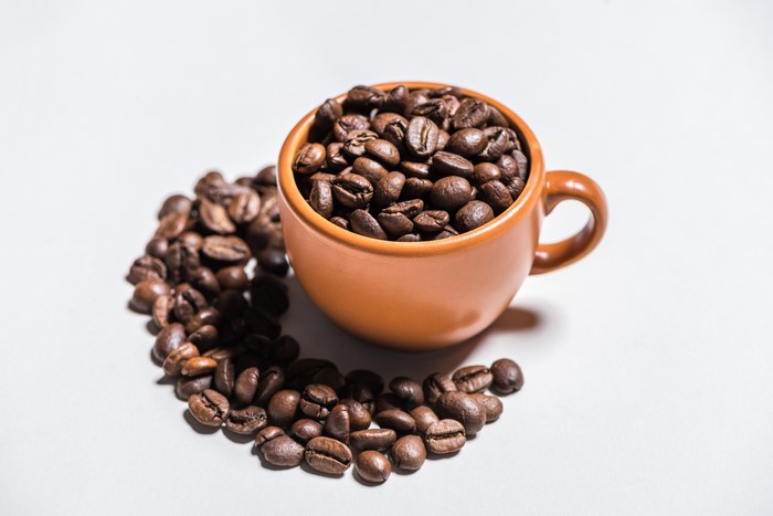 Coffee beans in a cup on a gray background