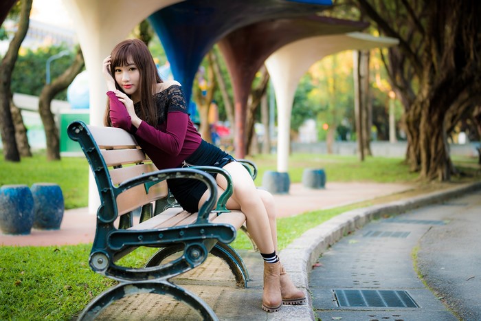 Asian woman sitting on a park bench