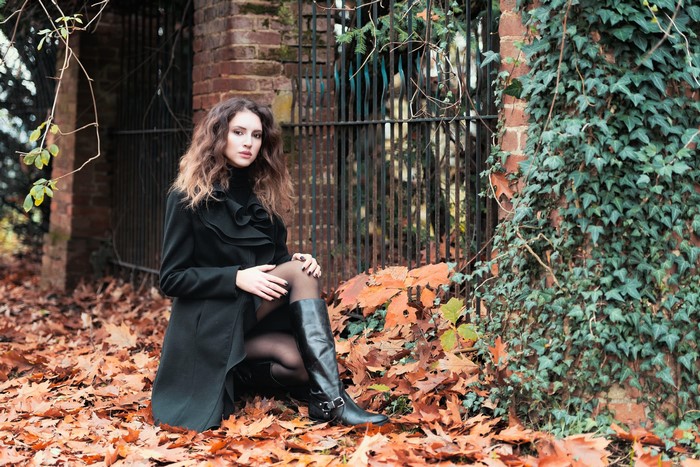 Woman in black coat sitting in autumn foliage