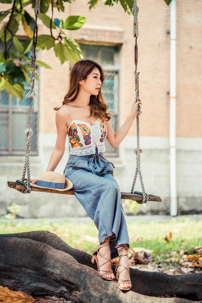 Asian woman with brown hair sitting on a swing