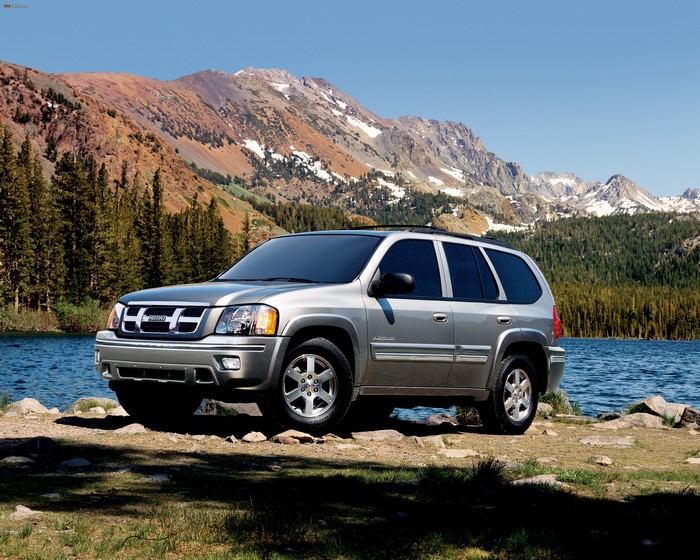 Silver Isuzu Ascender SUV parked by a lake with mountains