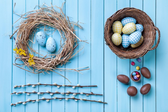 Easter Eggs in Nest and Wicker Basket on Wood Planks