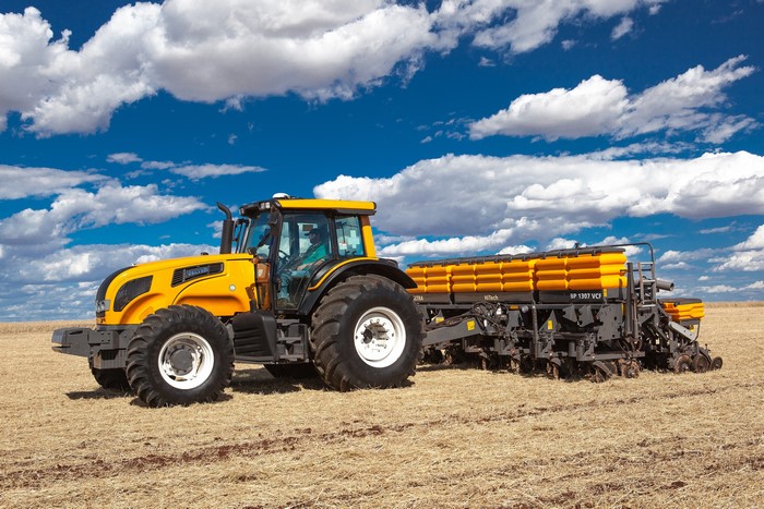 Yellow Valtra tractor pulling a planter in a field