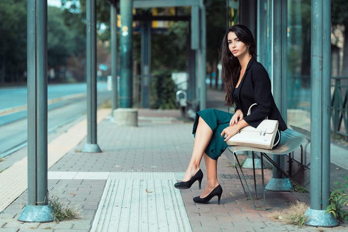 Brunette girl with handbag sitting on bench