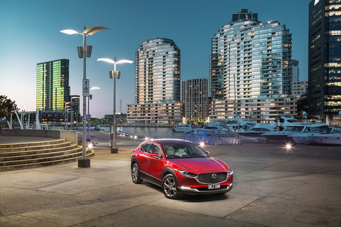 Red Mazda CX-30 parked by a harbor at dusk
