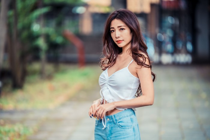 Asian woman with brown hair in white singlet and jeans
