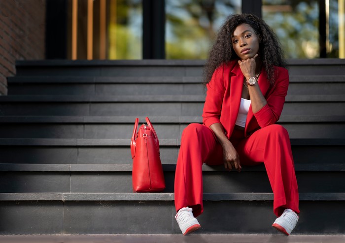 Woman in red suit sitting on stairs with handbag