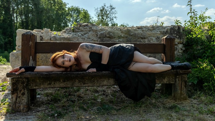 Woman with tattoos lying on a bench