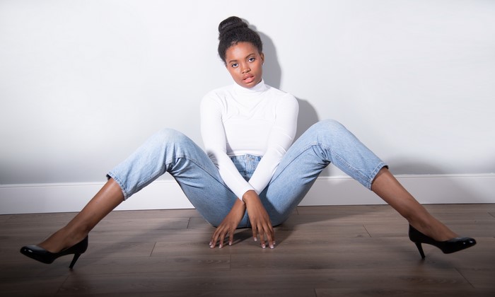 Woman in white turtleneck and jeans sitting on floor
