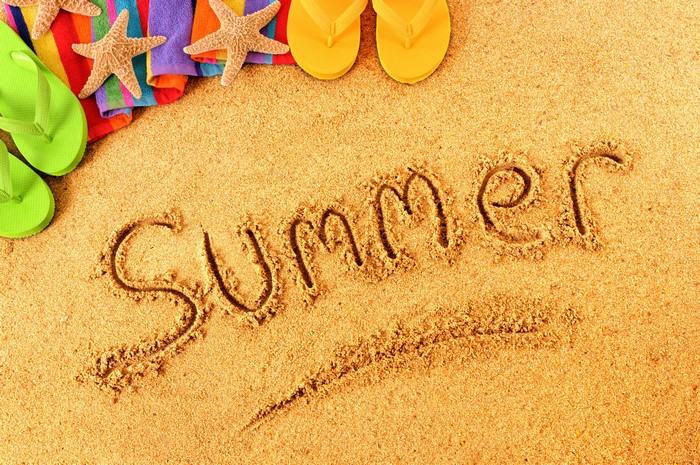 Summer written in sand with beach items