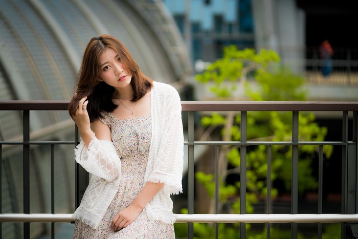 Asian woman with brown hair wearing a floral dress and white cardigan