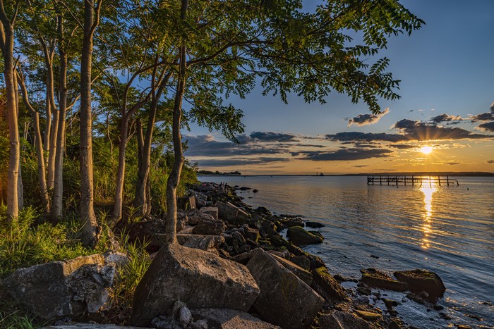 Sunset over bay with trees and rocks in Brooklyn, USA