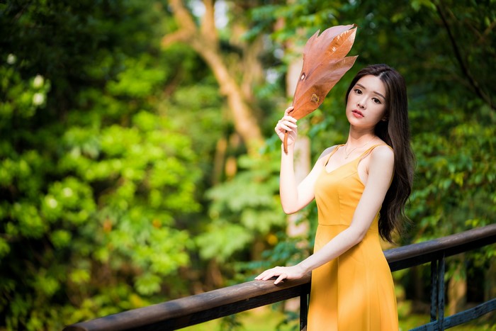 Asian woman in yellow dress holding a leaf
