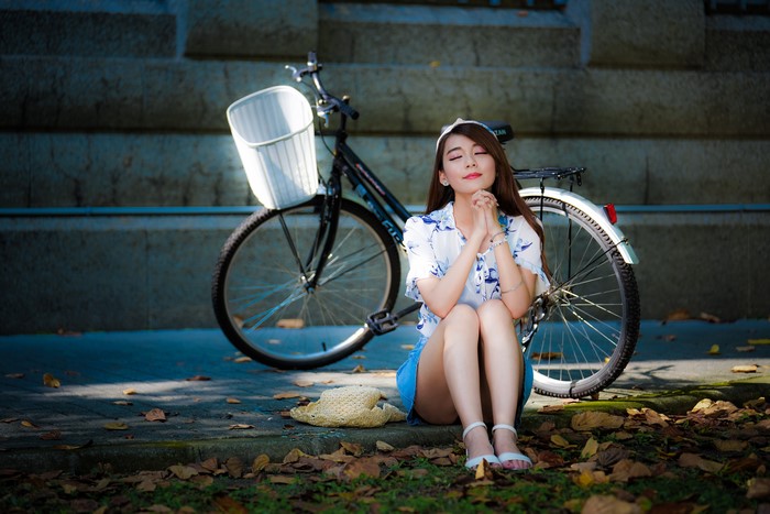 Asian woman sitting by a bicycle