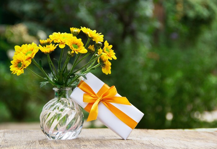 Yellow flowers in a vase with a gift box
