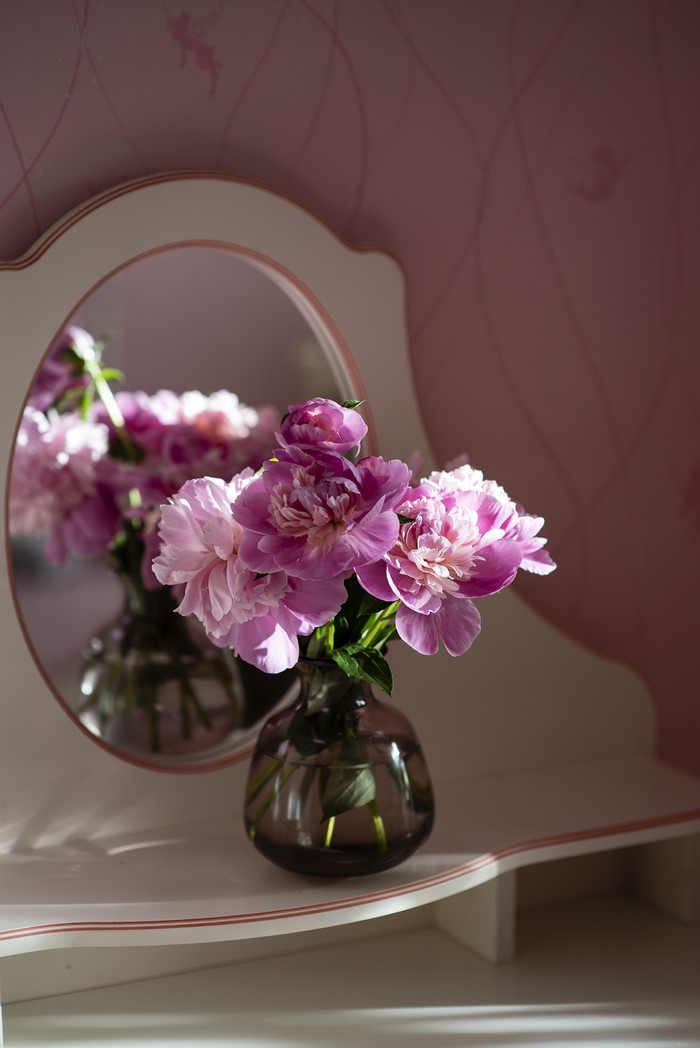 Pink peonies in a vase reflected in a mirror