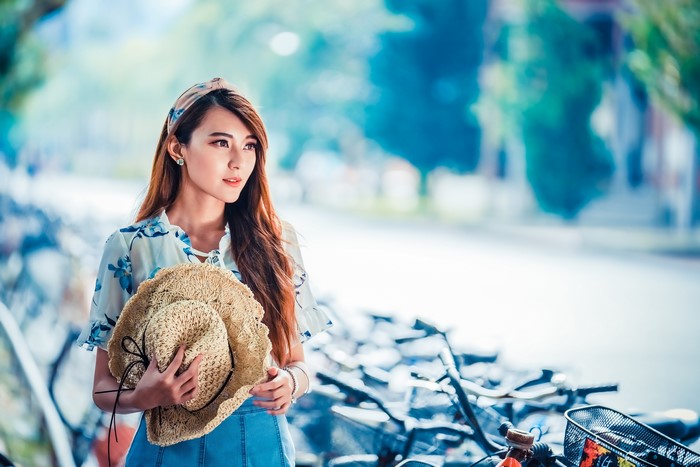 Asian woman with brown hair holding a hat