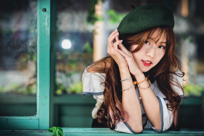 Asian woman with brown hair wearing a green beret