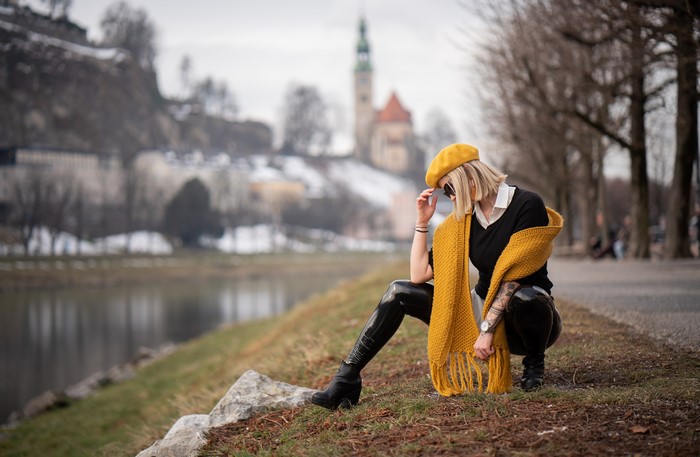 Woman with yellow beret and scarf sitting by river