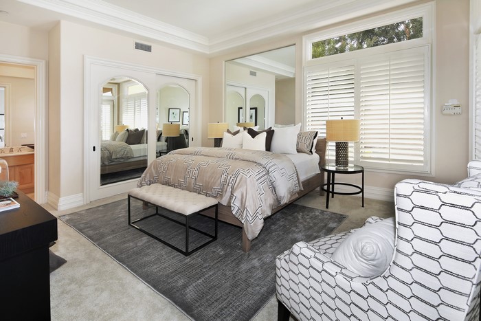 Bedroom with bed, lamps, and mirrored closet doors