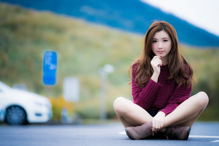 Woman sitting on asphalt with blurred background