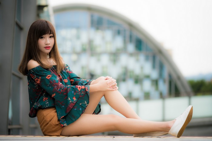 Asian woman with brown hair sitting outdoors
