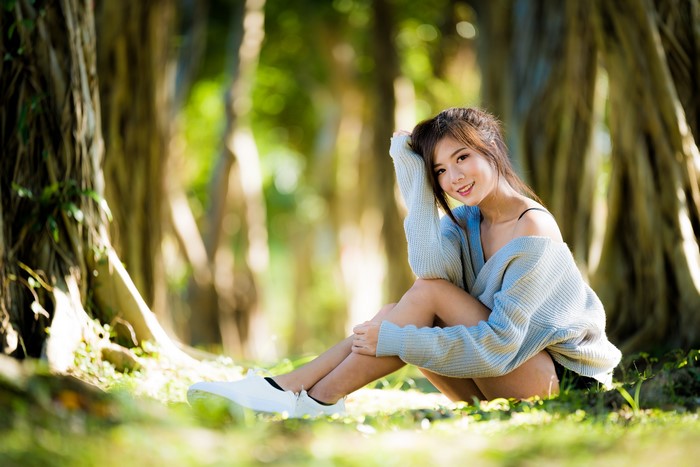 Asian Woman Sitting and Smiling with Sweater in Nature 4K