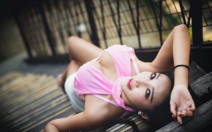 Brunette girl in pink top lying on wooden stairs