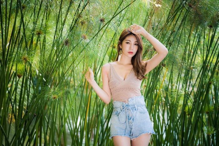 Asian woman in shorts posing near reeds
