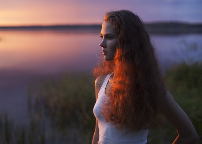 Redhead girl looking at sunset over lake