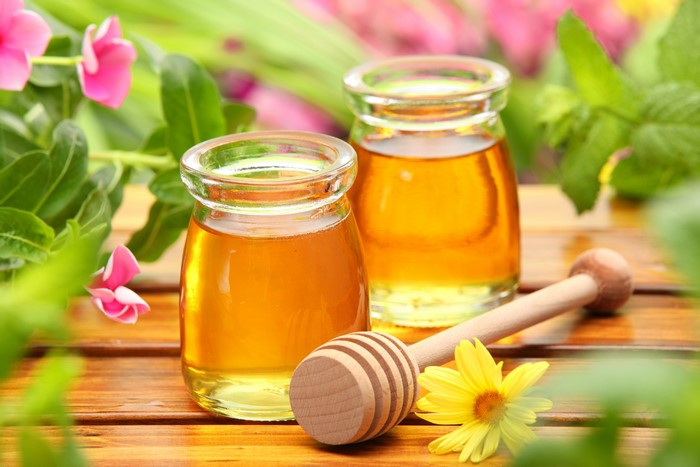 Honey in Jars with Honey Dipper and Flowers